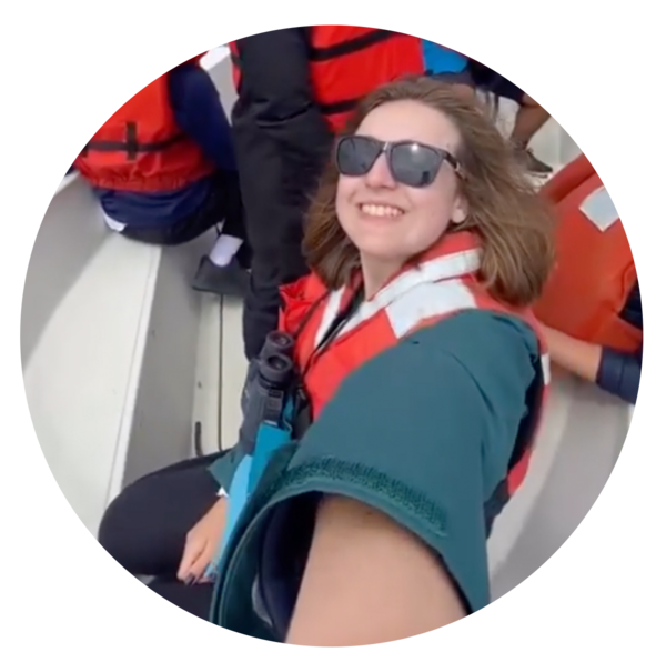 Judy sits in a boat wearing an orange PFD and sunglasses